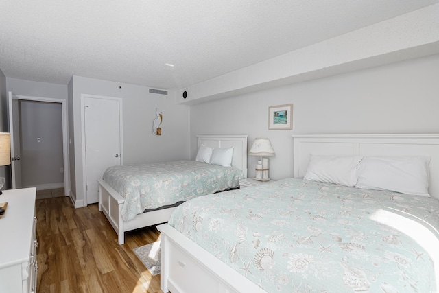 bedroom with a textured ceiling, visible vents, and wood finished floors