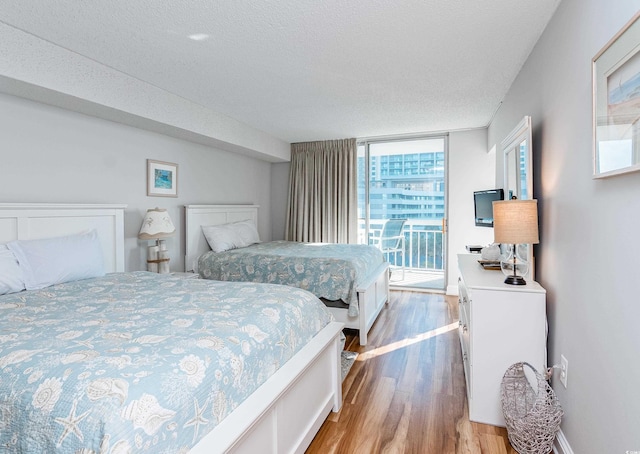 bedroom featuring a textured ceiling, multiple windows, and wood finished floors