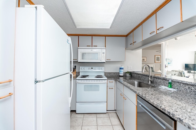 kitchen with white appliances, light tile patterned floors, a textured ceiling, and a sink