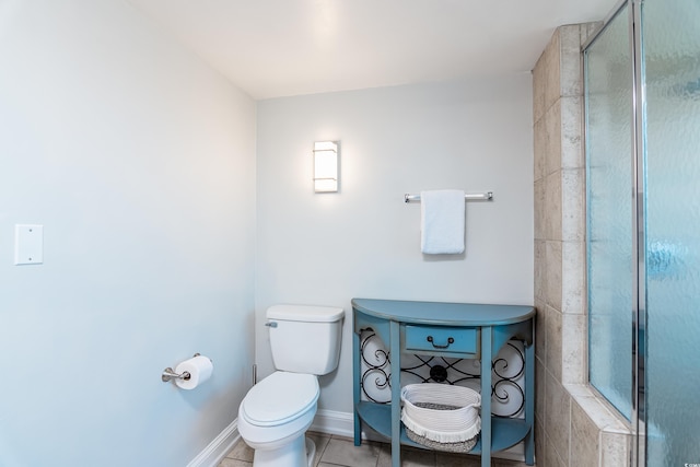 bathroom with baseboards, tile patterned flooring, toilet, and tiled shower