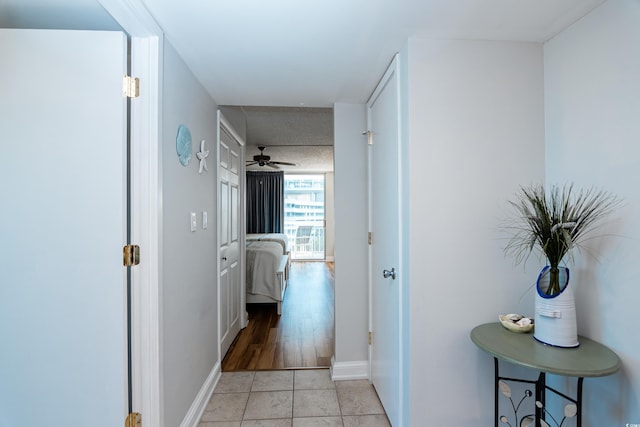 corridor with baseboards and light tile patterned floors