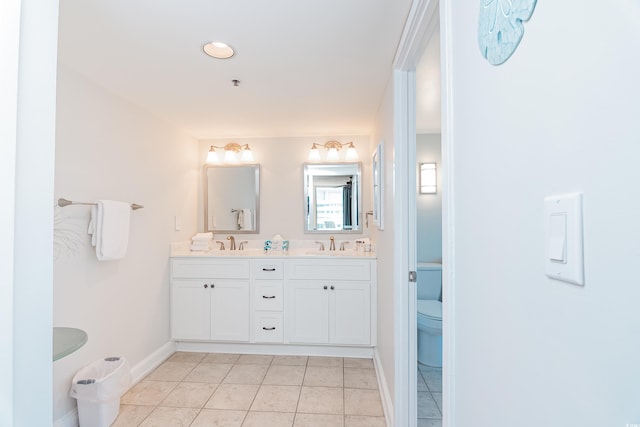 bathroom with a sink, tile patterned floors, toilet, and double vanity
