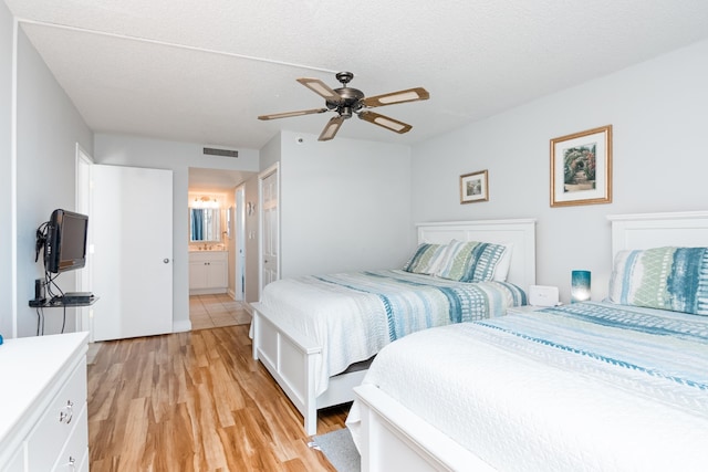 bedroom with visible vents, a ceiling fan, light wood finished floors, and ensuite bath