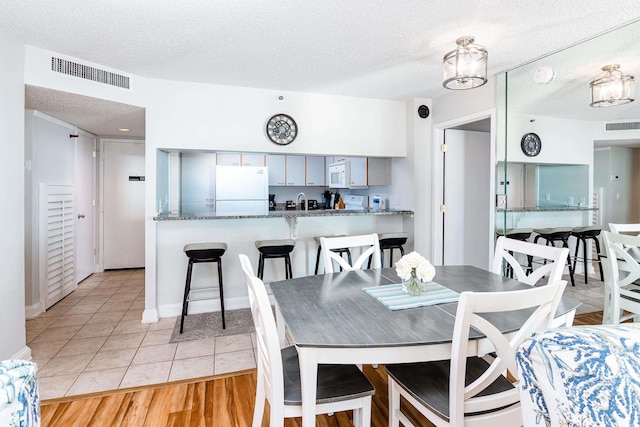 dining area featuring baseboards, a textured ceiling, visible vents, and light tile patterned floors