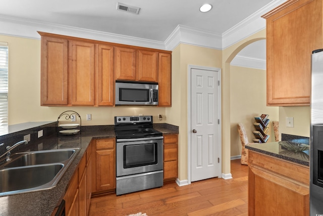 kitchen with light wood finished floors, visible vents, a sink, arched walkways, and appliances with stainless steel finishes