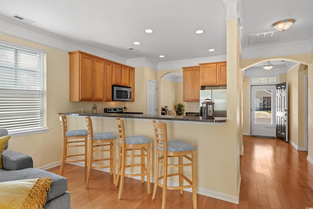 kitchen with light wood finished floors, appliances with stainless steel finishes, visible vents, and arched walkways
