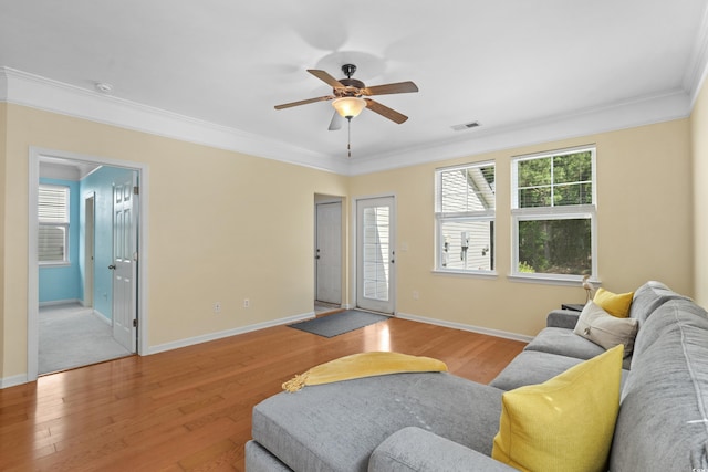 living room with wood finished floors, a wealth of natural light, baseboards, ceiling fan, and ornamental molding
