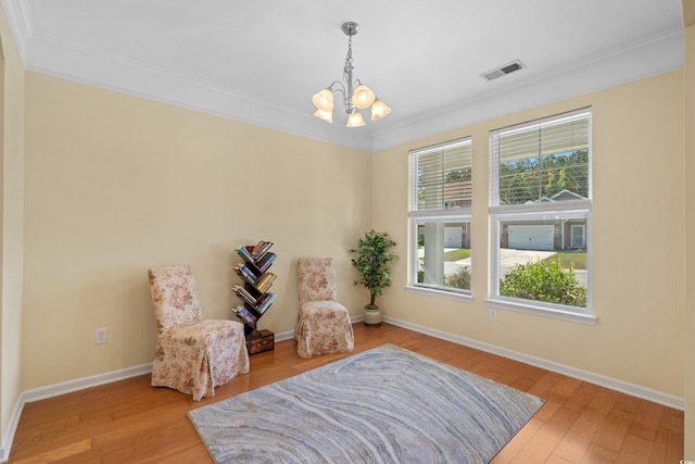 sitting room with an inviting chandelier, visible vents, wood finished floors, and ornamental molding