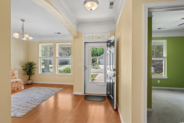 entryway with baseboards, a wealth of natural light, ornamental molding, and a chandelier