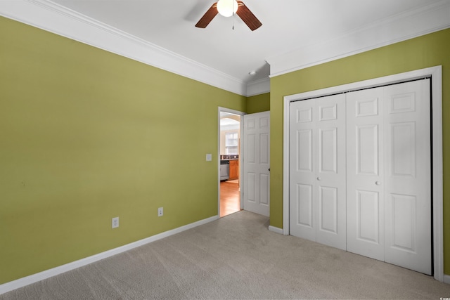 unfurnished bedroom featuring a closet, baseboards, ornamental molding, ceiling fan, and light colored carpet