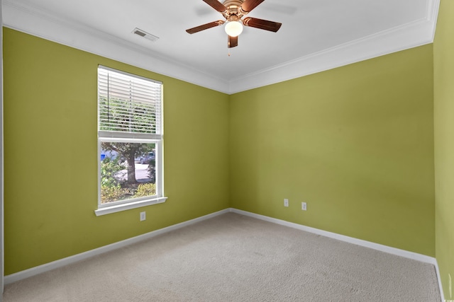carpeted spare room with visible vents, baseboards, a ceiling fan, and ornamental molding