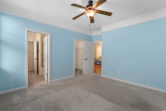 unfurnished bedroom featuring baseboards, crown molding, carpet, and a walk in closet