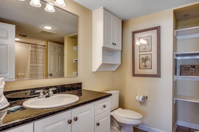bathroom with vanity, toilet, a textured ceiling, and visible vents