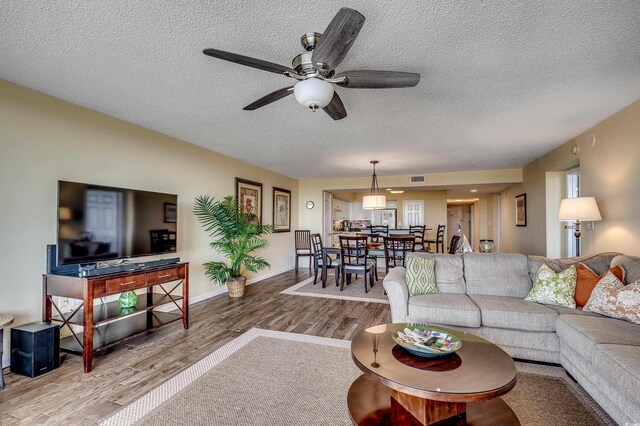 2151 Bridge View Ct Unit 2-803, North Myrtle Beach, SC 29582 - living room featuring a textured ceiling, a ceiling fan, baseboards, wood finished floors, and visible vents