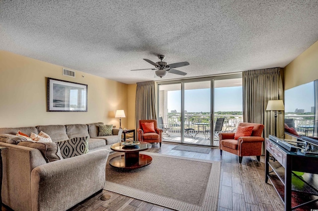 living area featuring a ceiling fan, hardwood / wood-style flooring, a textured ceiling, and visible vents