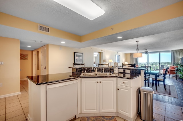 kitchen featuring white dishwasher, open floor plan, a center island with sink, white cabinetry, and a sink