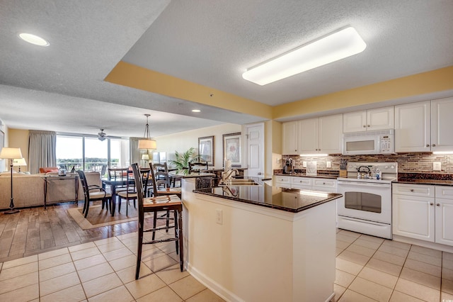 kitchen featuring white appliances, white cabinetry, dark countertops, and open floor plan