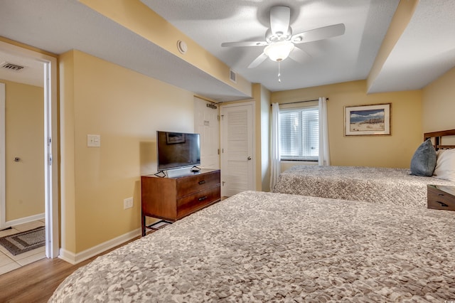 bedroom featuring baseboards, ceiling fan, wood finished floors, and visible vents