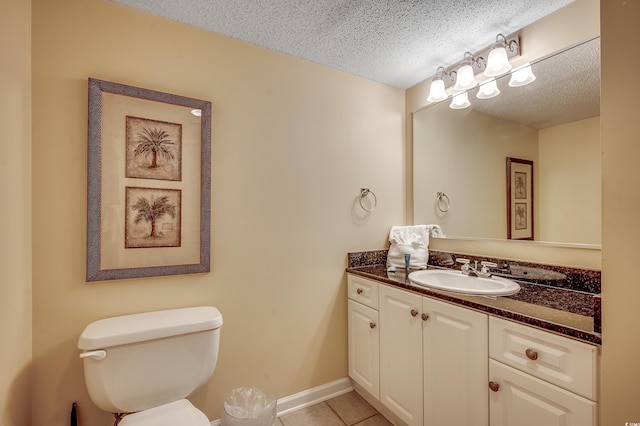 half bath with tile patterned flooring, vanity, toilet, baseboards, and a textured ceiling