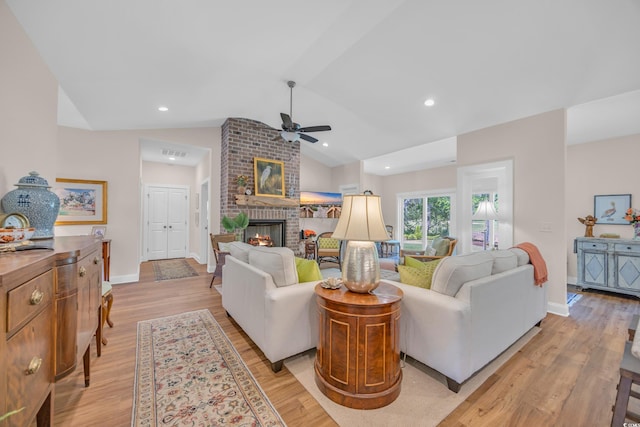 living area featuring a brick fireplace, ceiling fan, light wood-style floors, and vaulted ceiling