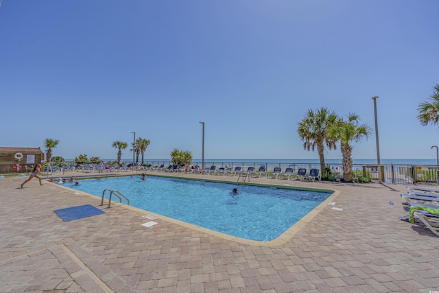 community pool with a patio area and fence
