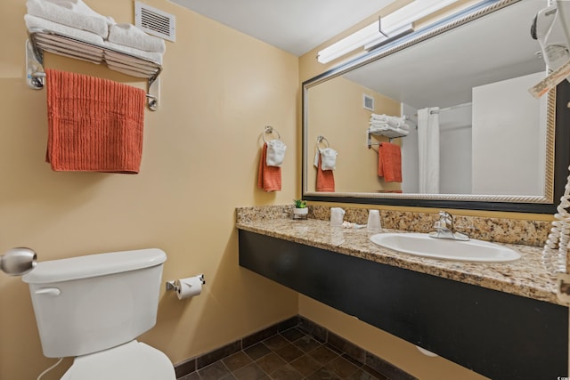 bathroom with vanity, toilet, baseboards, and visible vents