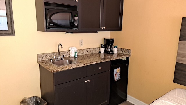 bar with fridge, indoor wet bar, a sink, and black microwave