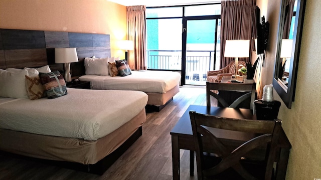 bedroom with a textured wall, dark wood-style floors, and access to exterior