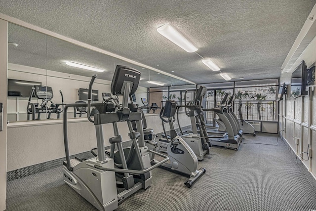 gym featuring baseboards, carpet floors, and a textured ceiling
