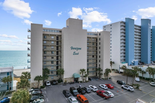 view of apartment building / complex with uncovered parking and a water view
