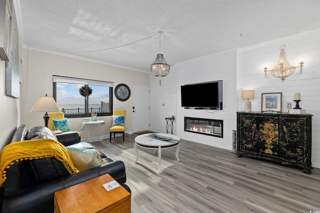 living area with wood finished floors, a large fireplace, a textured ceiling, and crown molding