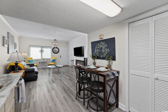 dining room featuring light wood-style flooring, a textured ceiling, baseboards, and a chandelier