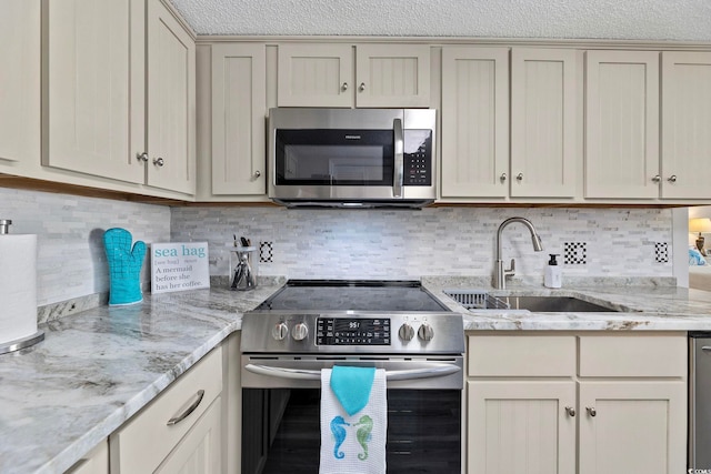 kitchen with stainless steel appliances, a sink, decorative backsplash, and light stone counters