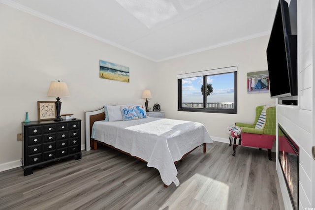 bedroom featuring wood finished floors, crown molding, and baseboards