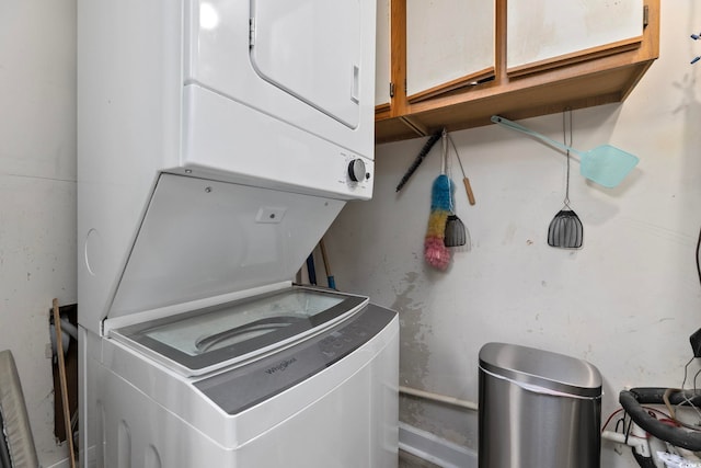 laundry room featuring stacked washer / drying machine and cabinet space
