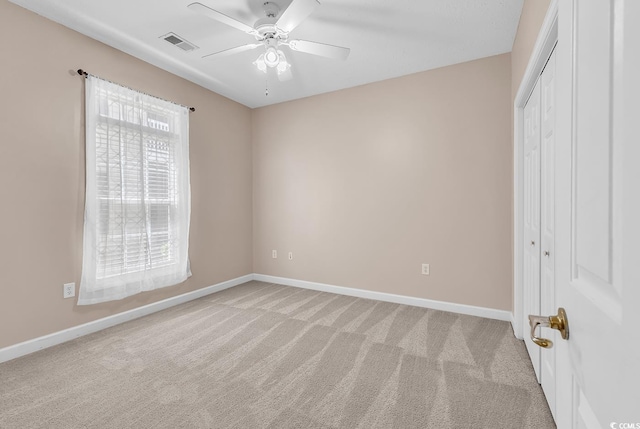 unfurnished bedroom featuring light colored carpet, baseboards, visible vents, and a closet