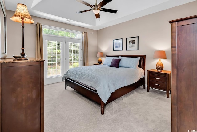 bedroom featuring a tray ceiling, light colored carpet, access to exterior, and visible vents