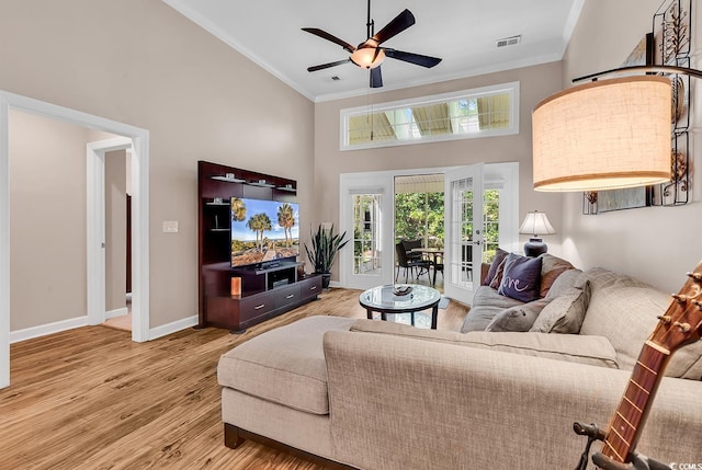 living area featuring visible vents, crown molding, a towering ceiling, wood finished floors, and french doors