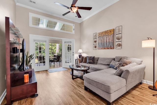 living room with ceiling fan, french doors, crown molding, wood finished floors, and a high ceiling