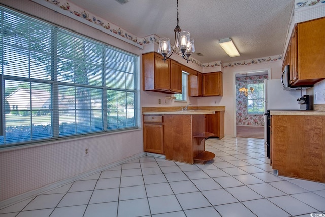802 Mockingbird Ct, Murrells Inlet, SC 29576 - kitchen with light countertops, stainless steel microwave, brown cabinets, a notable chandelier, and decorative light fixtures