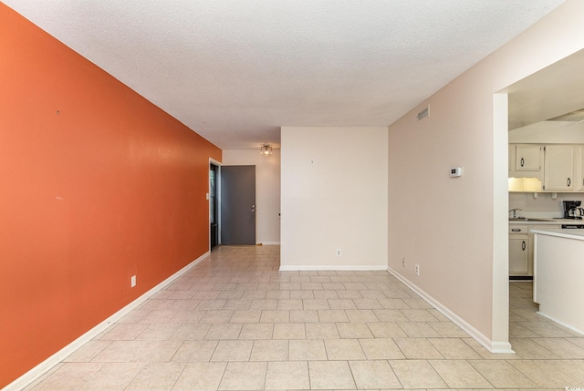 unfurnished room featuring baseboards, a sink, and a textured ceiling