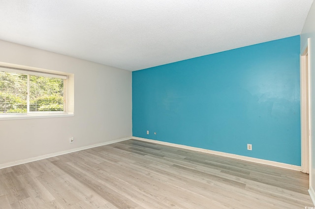 empty room featuring a textured ceiling, baseboards, and wood finished floors