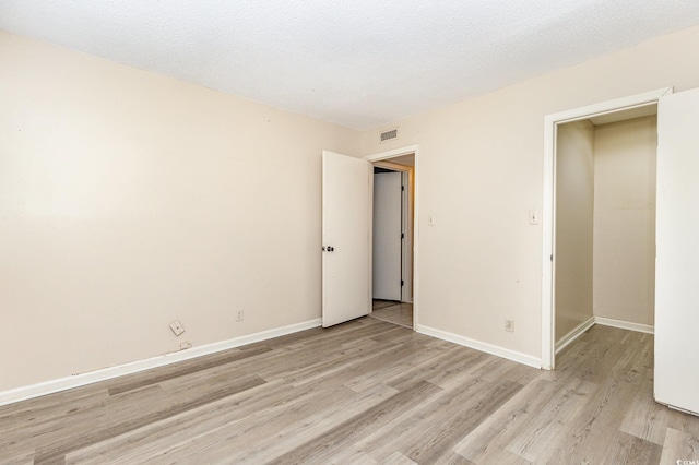 unfurnished bedroom featuring baseboards, visible vents, and light wood finished floors