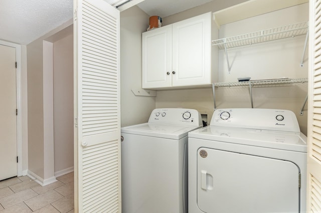 washroom featuring cabinet space, light tile patterned floors, baseboards, and washer and clothes dryer