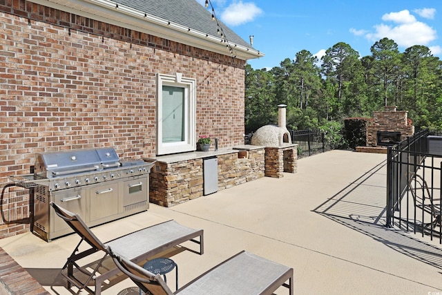 view of patio featuring area for grilling, an outdoor stone fireplace, and a grill