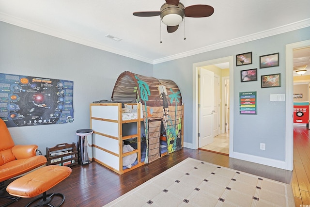 interior space with ceiling fan, visible vents, baseboards, ornamental molding, and hardwood / wood-style floors