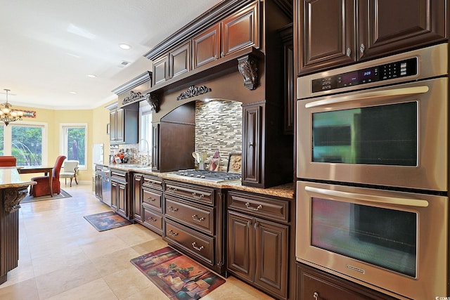 kitchen featuring an inviting chandelier, decorative backsplash, dark brown cabinets, a sink, and stainless steel appliances