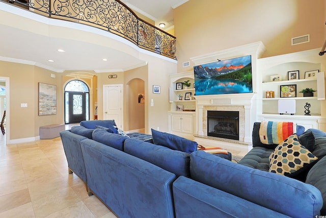 living room featuring crown molding, a high ceiling, arched walkways, built in features, and baseboards
