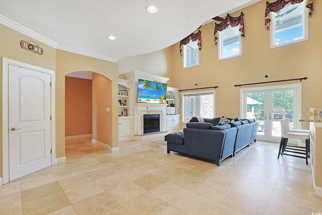 living area with crown molding, arched walkways, plenty of natural light, and light tile patterned flooring