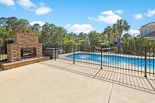 view of pool featuring fence, a fenced in pool, a patio area, and an outdoor stone fireplace